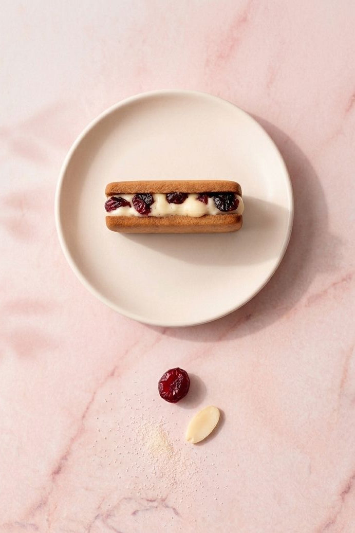 Almond cookie sand with cranberries cream on a white plate on a pink marble surface