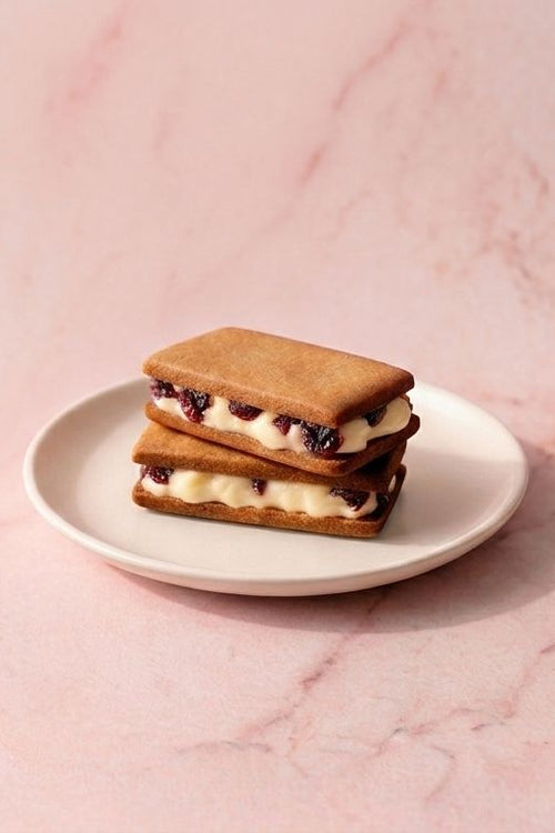 Stack of cookie sandwiches on a white plate with a pink marble background