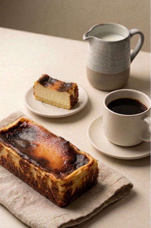 full cheesecake, slice of cheesecake, and cup of coffee on a table with a neutral background